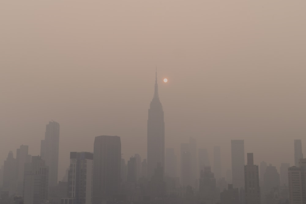 a foggy city skyline with the sun in the distance