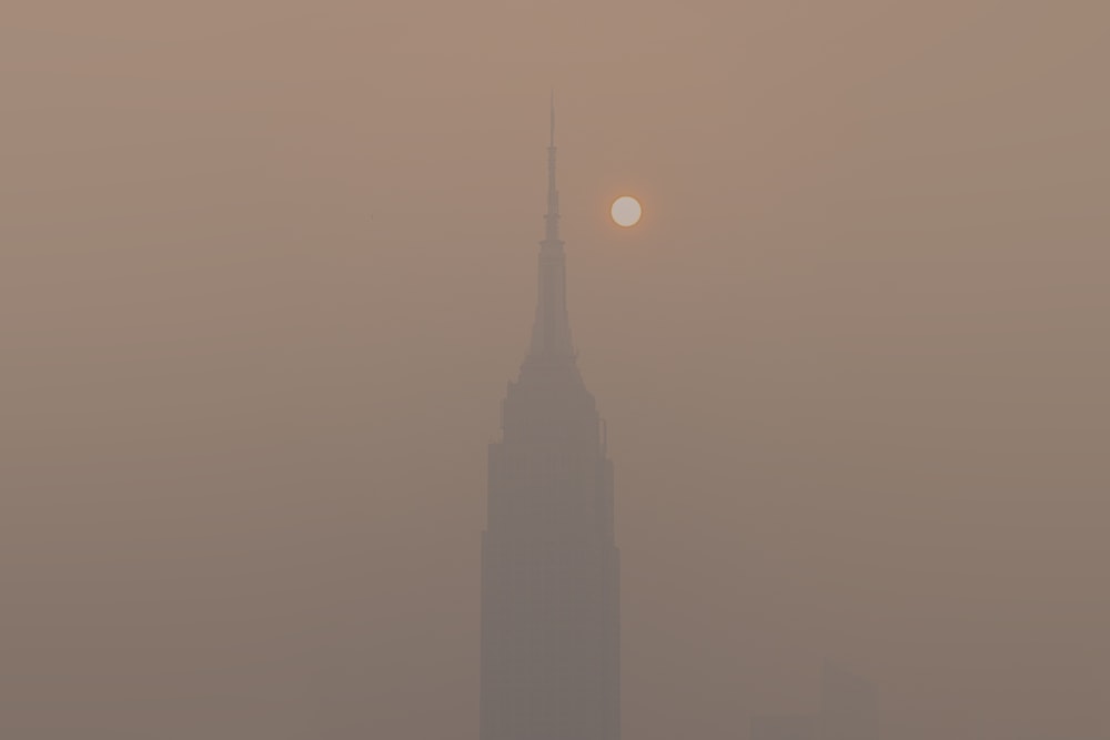 a foggy skyline with a tall building in the distance