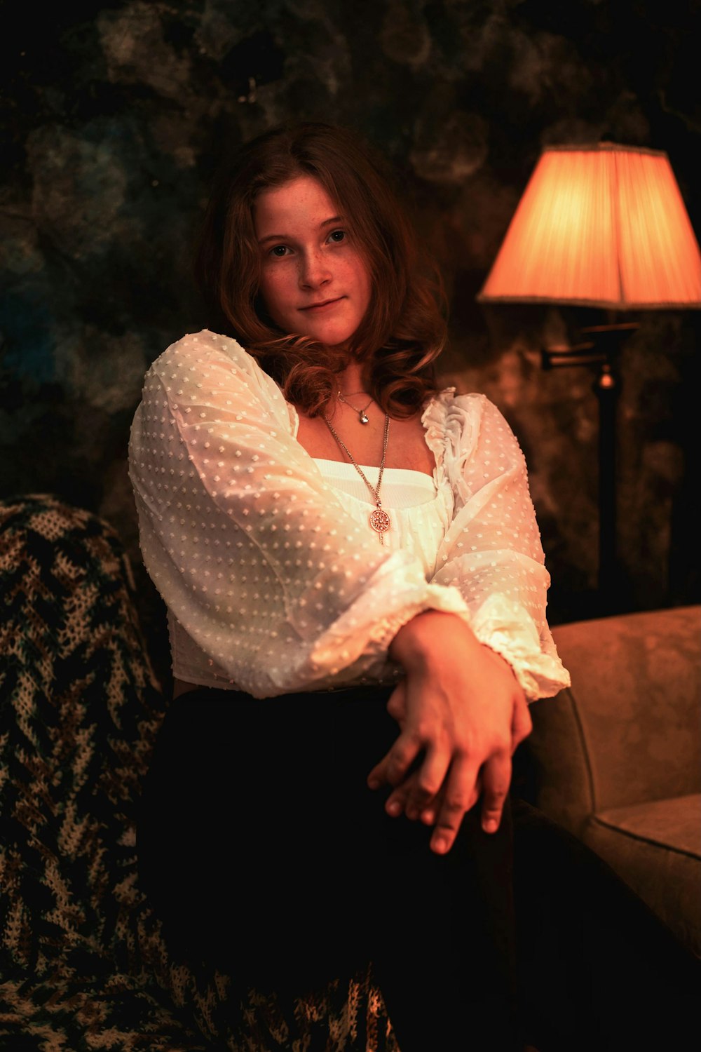 a woman sitting on a couch next to a lamp