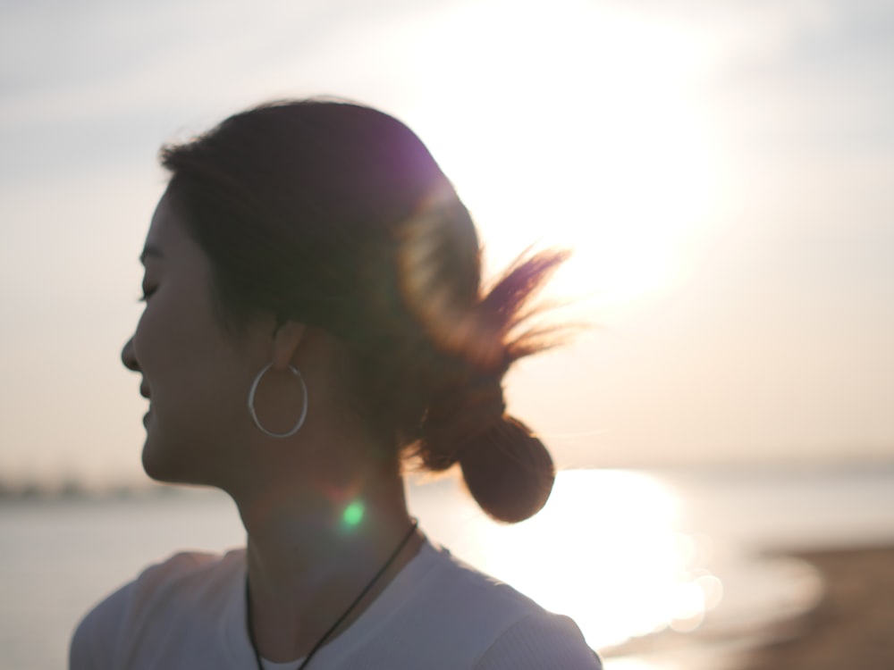 a woman standing on a beach with the sun in the background