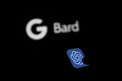 A low-light image featuring a blurred, glowing white Google Bard logo in the background and a clear OpenAI logo with a knot design in the foreground, set against a dark background.
