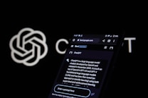 A smartphone screen displays a web page about ChatGPT, featuring a black background with white text. The screen includes a search bar and various interface icons at the top. In the background, an OpenAI logo is partially visible against a black backdrop.