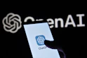 a person holding a cell phone in front of a logo