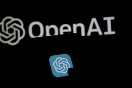 A close-up of a luminous, stylized logo resembling a circular knot with a gradient blue background, prominently displayed on a screen. Behind it, the word 'OpenAI' is visible, illuminated against a dark backdrop.