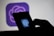 A hand holding a mobile device with a logo displayed on the screen, set against a blurred backdrop of the same logo.