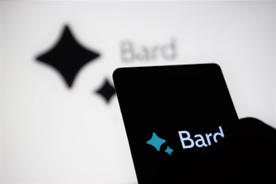 An illuminated smartphone screen displaying the word 'Bard' and a stylized four-pointed star logo. The same text and logo are also visible, though blurred, in the background.