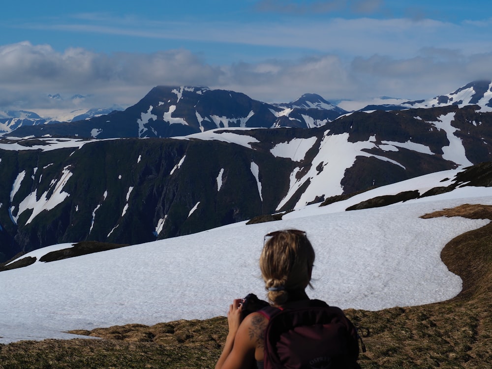 a woman with a backpack is looking at the mountains