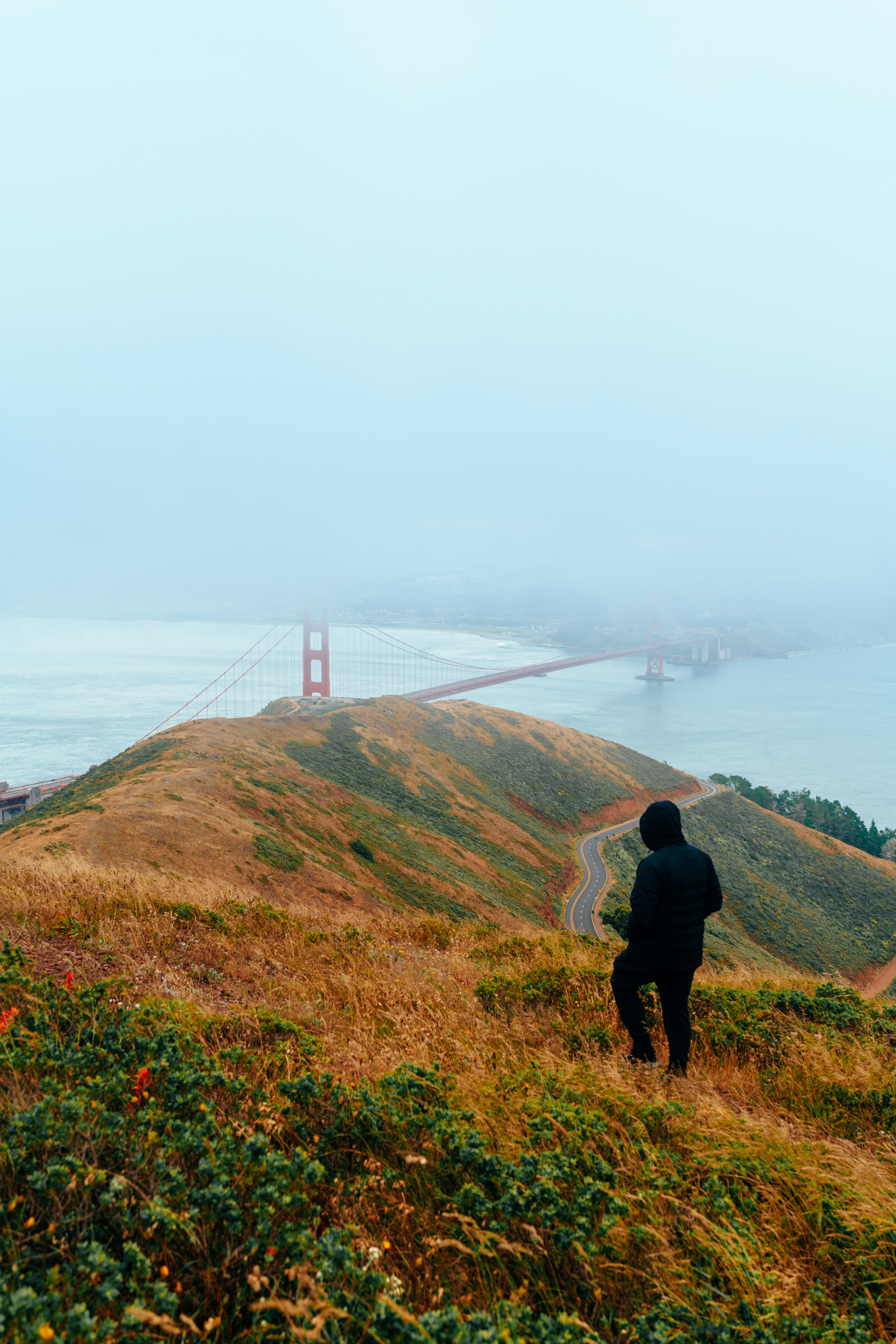 a man standing on top of a hill next to a bridge