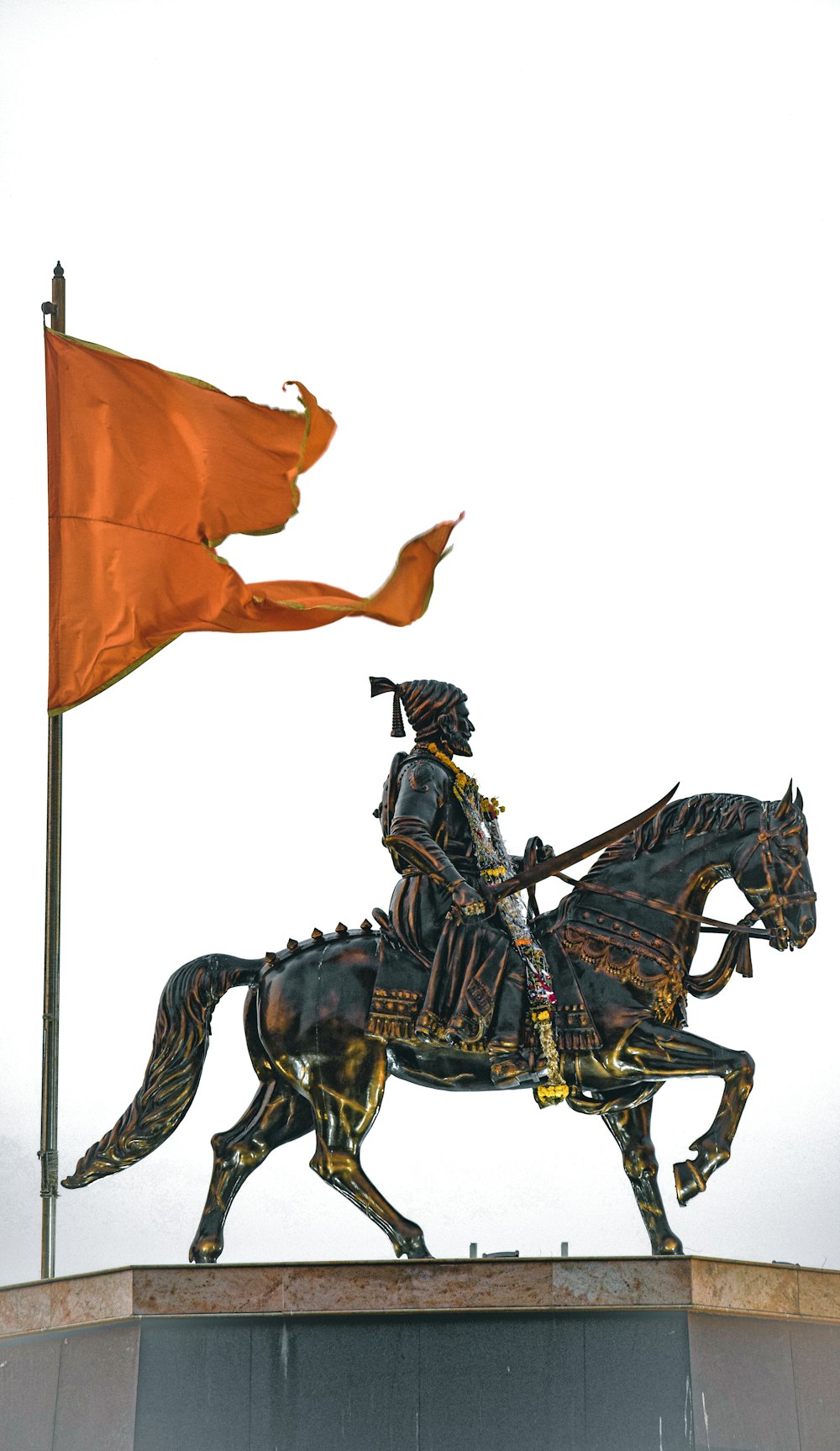 a statue of a man riding a horse next to a flag
