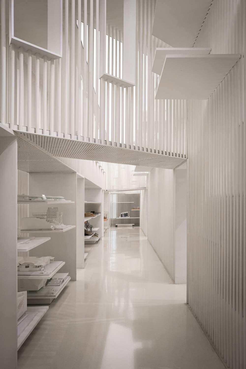 a long hallway with white walls and a white staircase