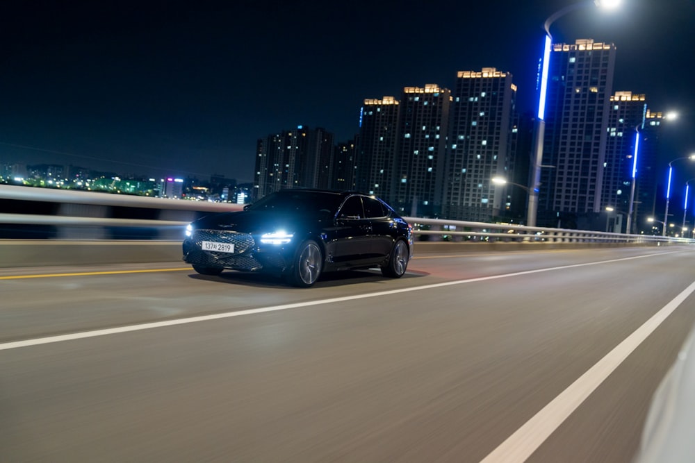 a black car driving down a city street at night