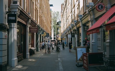 a group of people walking down a street next to tall buildings