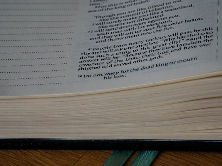A vintage leather-bound book open to a page of philosophical text, resting on a wooden desk with soft natural light.
