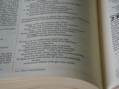 Close-up of hands holding an open Bible with a gentle light shining on the pages.