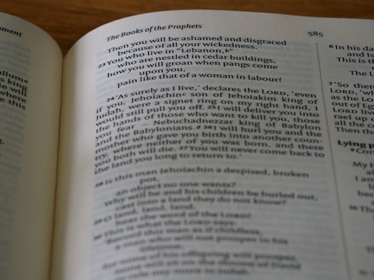 An open book displaying a page with religious text under the heading 'The Books of the Prophets.' The page contains verses that include mentions of Lebanon, Jehoiakim, and Nebuchadnezzar. The text layout is in two columns, with a line number visible at the top right.