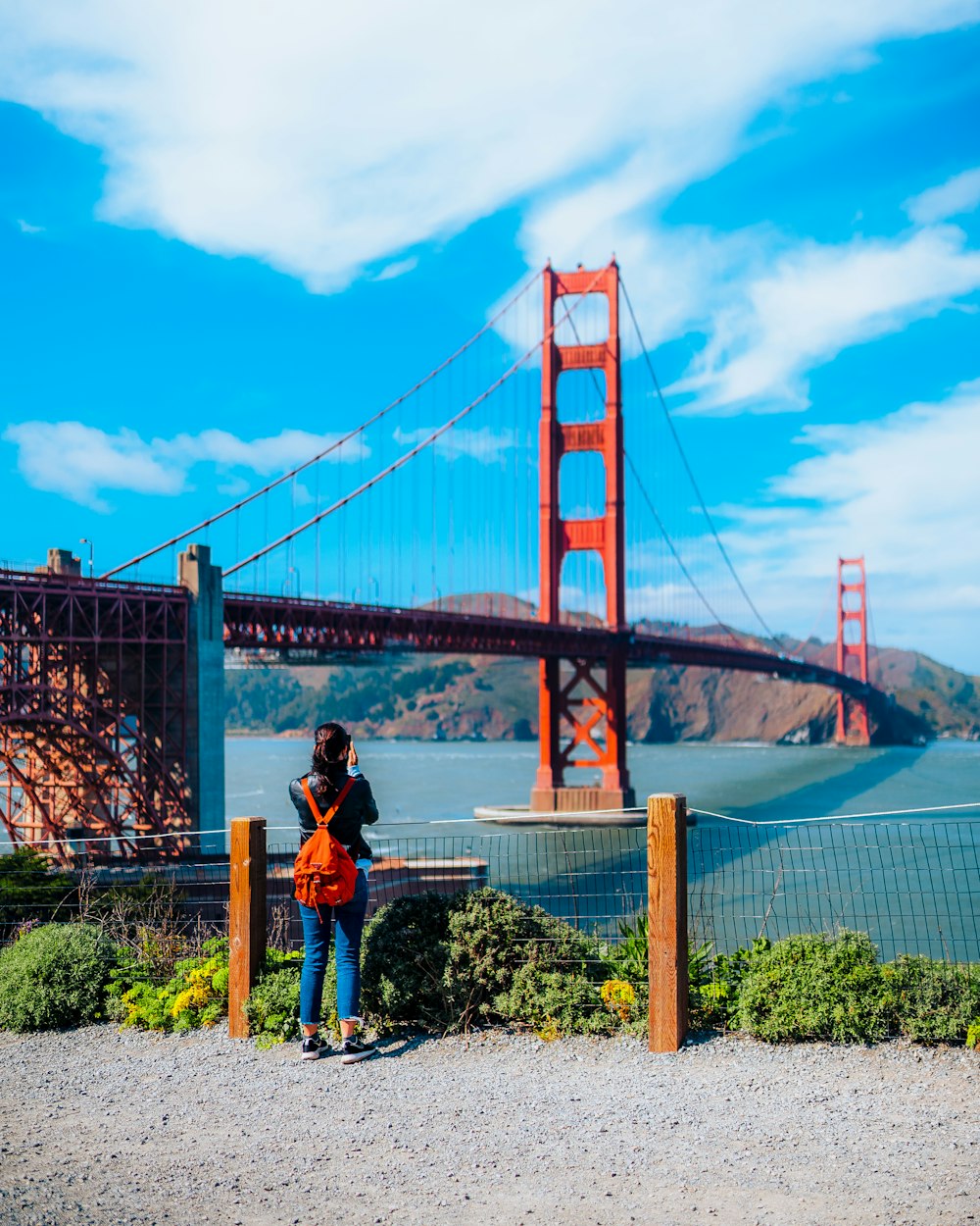 a woman standing in front of the golden gate bridge