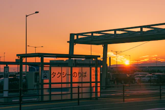 A friendly taxi driver standing beside a clean car in front of Amsterdam canals at sunset