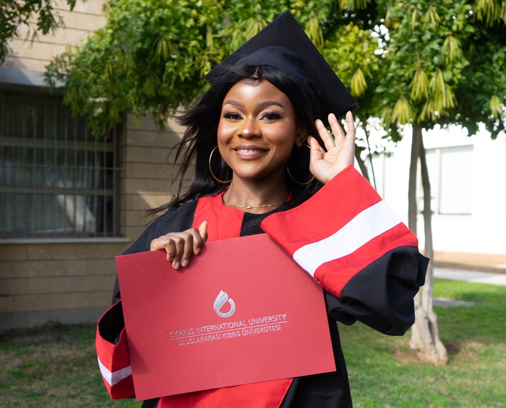 Una mujer con una gorra de graduación y una bata sosteniendo un pedazo de papel