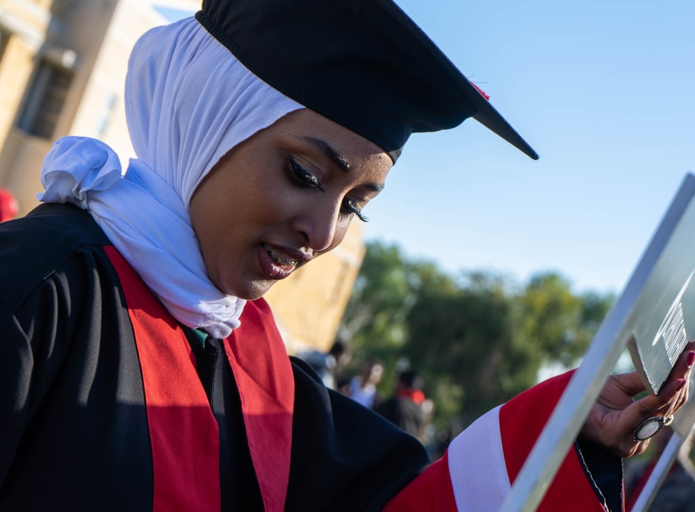 a woman in a graduation cap and gown looking at her cell phone