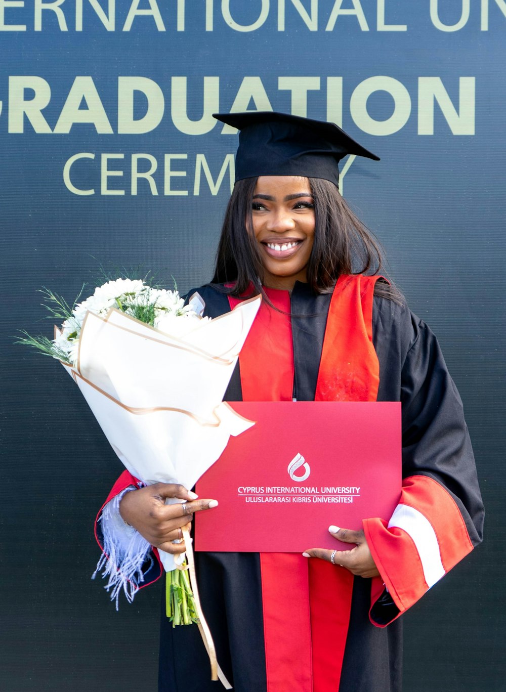 a woman in a graduation gown holding a bouquet of flowers