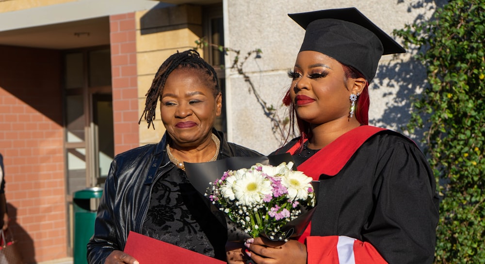 a woman in a graduation gown holding a bouquet of flowers