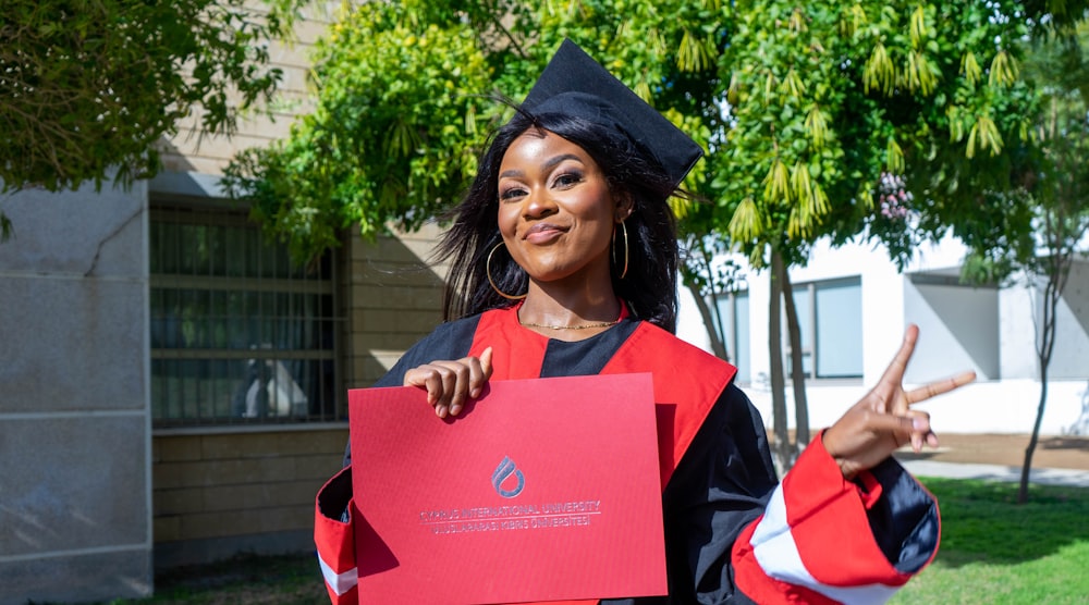 a woman in a graduation gown holding a red piece of paper