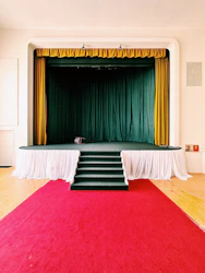 a stage with a red carpet and a green curtain