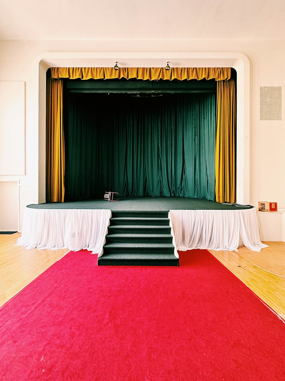 a stage with a red carpet and a green curtain