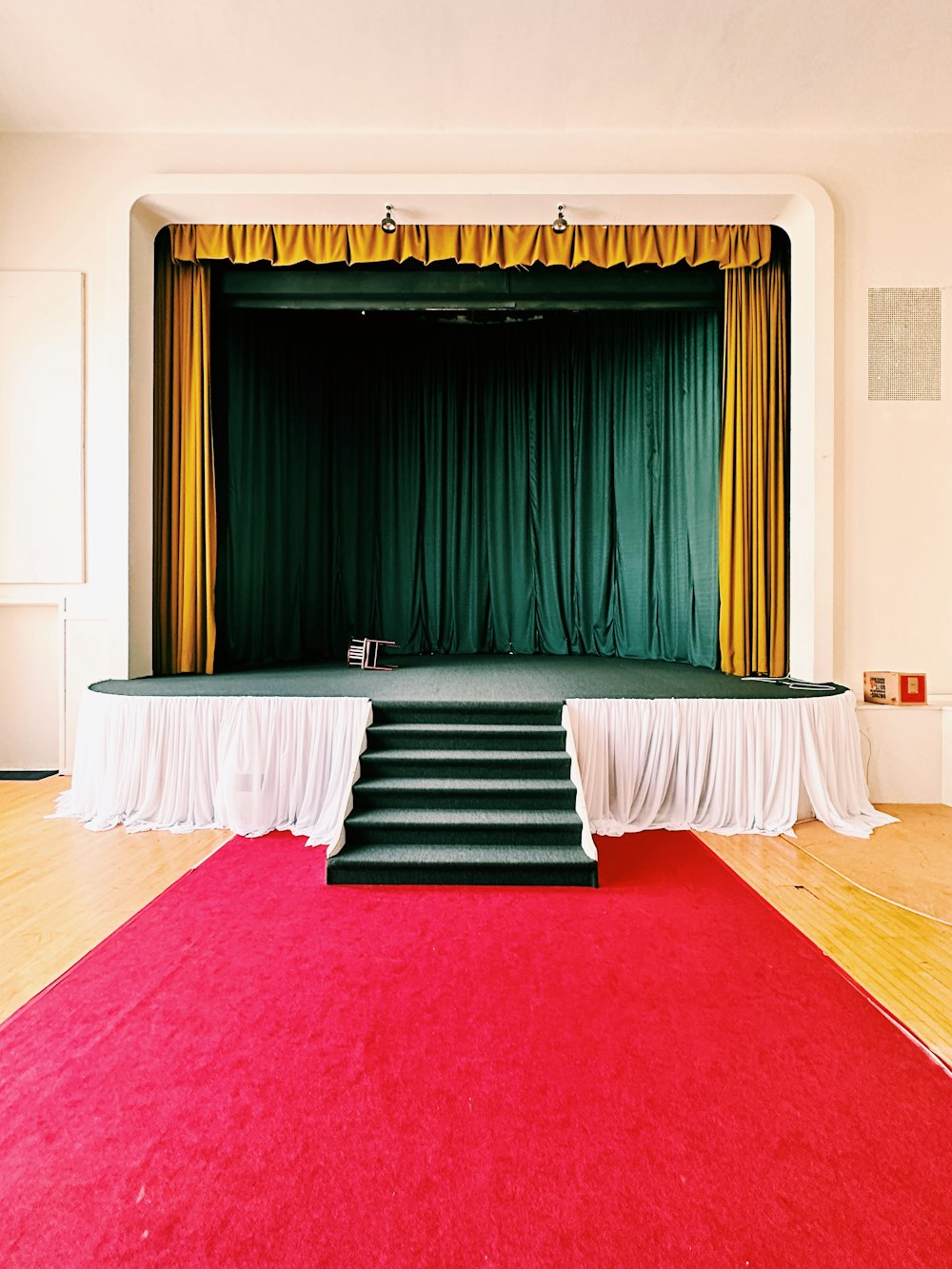 Un escenario con una alfombra roja y una cortina verde