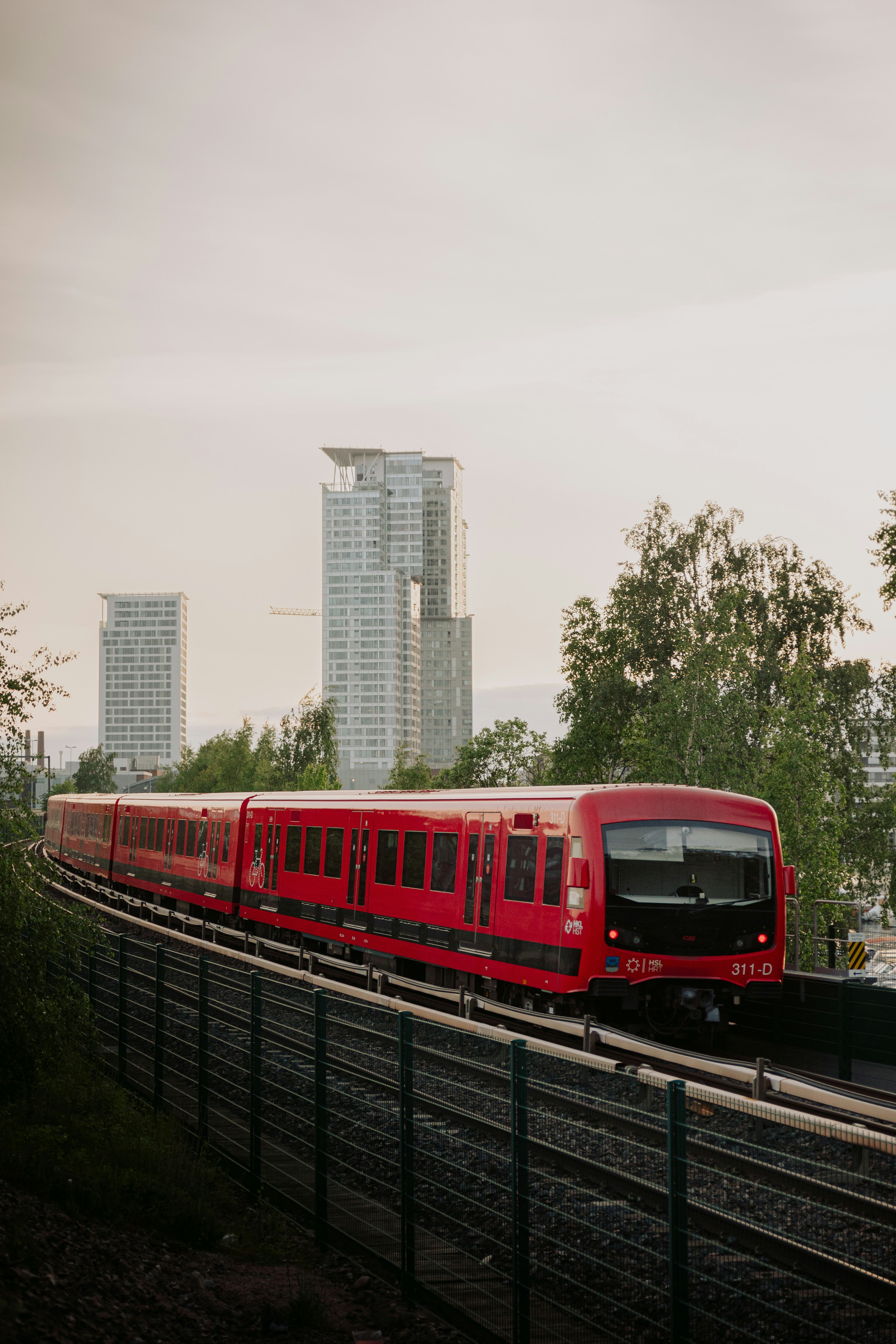 a red train traveling down train tracks next to tall buildings