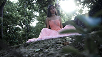A serene moment of a woman meditating outdoors at sunset, wrapped in soft pink hues.