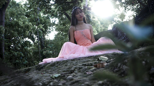 A serene moment of a woman meditating outdoors at sunset, wrapped in soft pink hues.