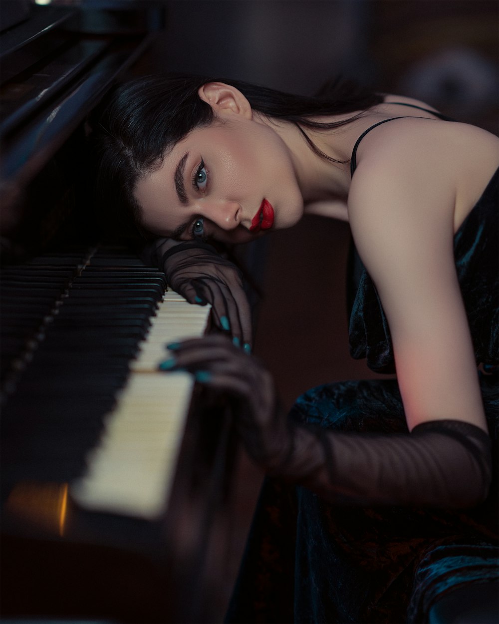 a woman in a black dress sitting at a piano