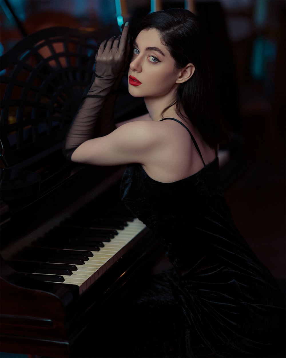 a woman in a black dress sitting at a piano