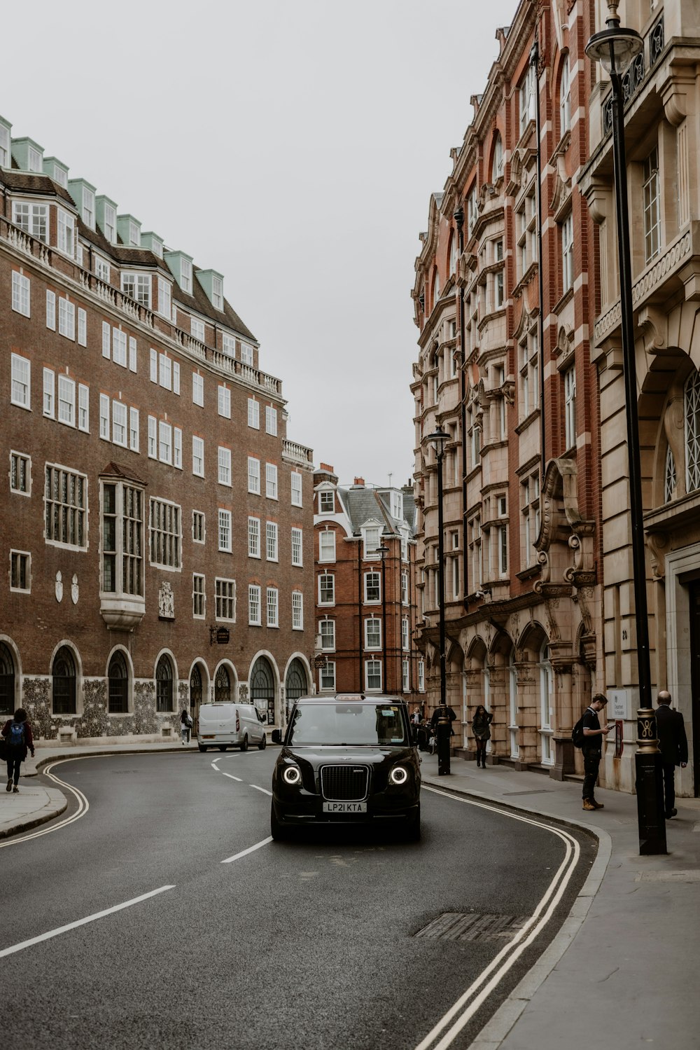 a black car driving down a street next to tall buildings