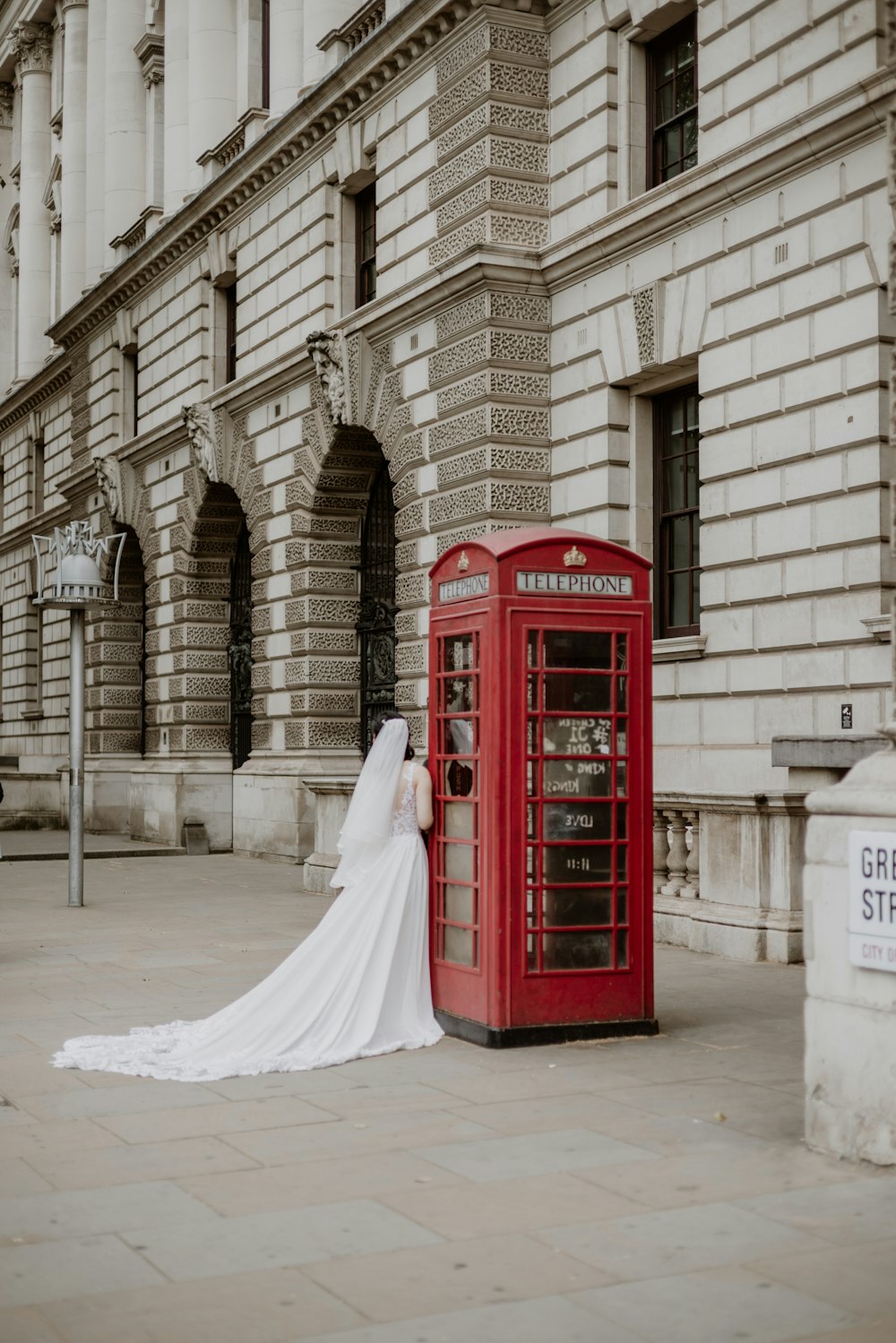 a bride standing next to a red phone booth