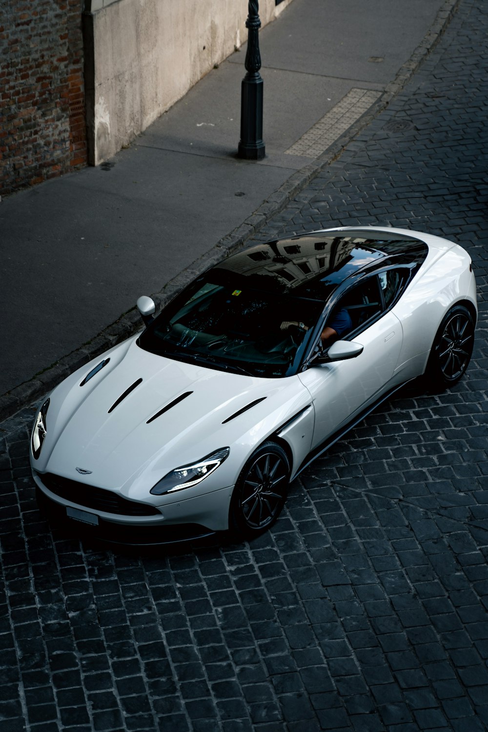 a white sports car parked on a cobblestone street