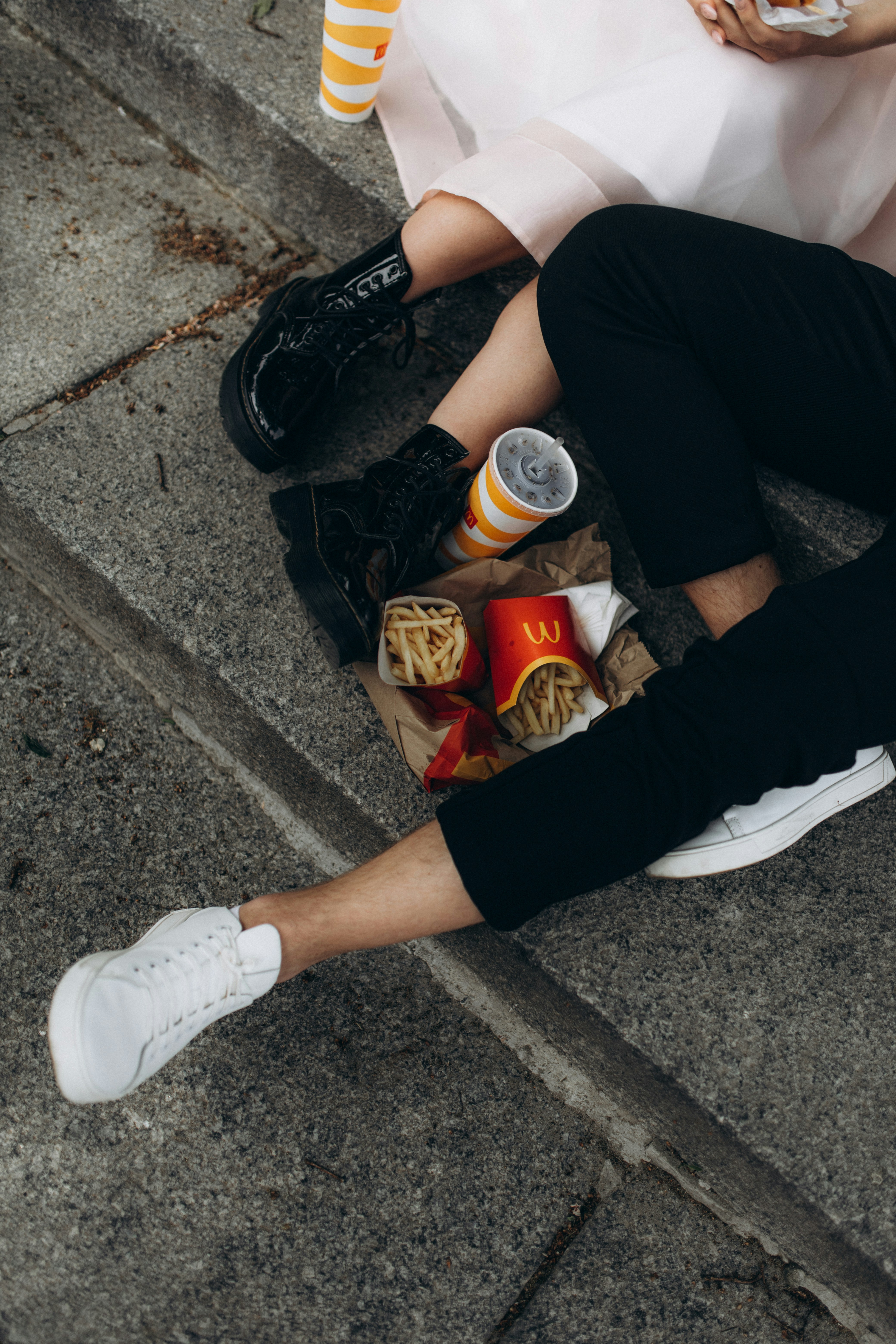 a man and woman sitting on the ground eating food