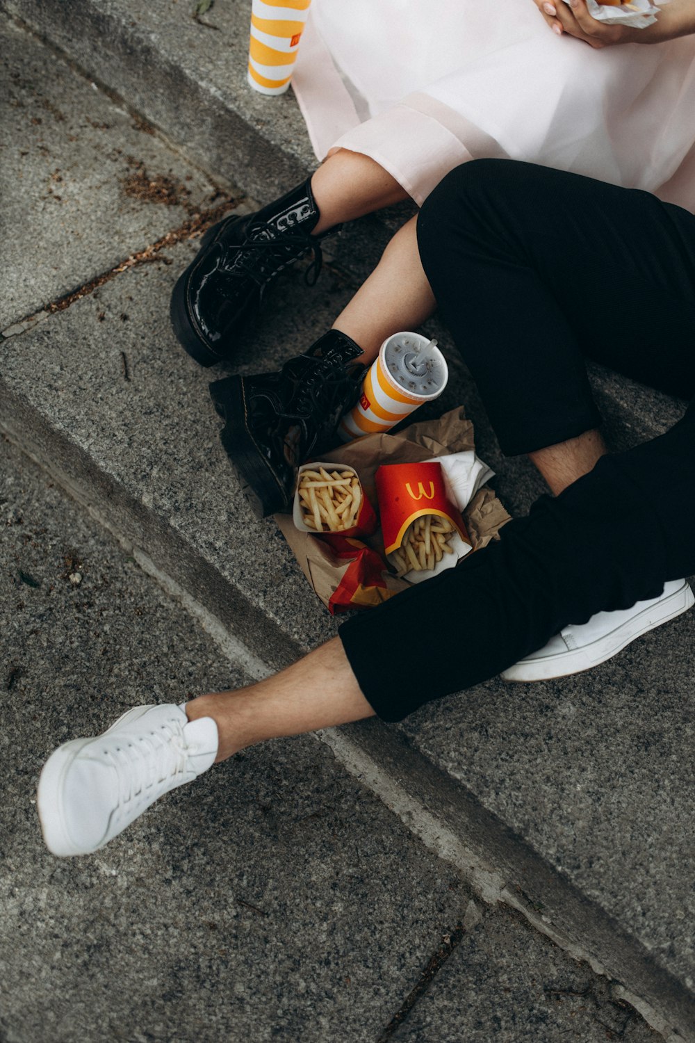 a man and woman sitting on the ground eating food