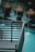 The image contains a decorative outdoor water feature with several spherical terracotta pots, each streaming water into a pool. The water is a striking turquoise, contrasting with the dark metal railing in the foreground.
