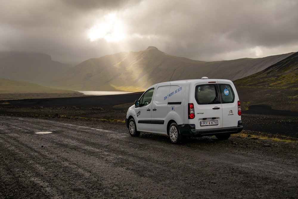 a white van parked on the side of a dirt road