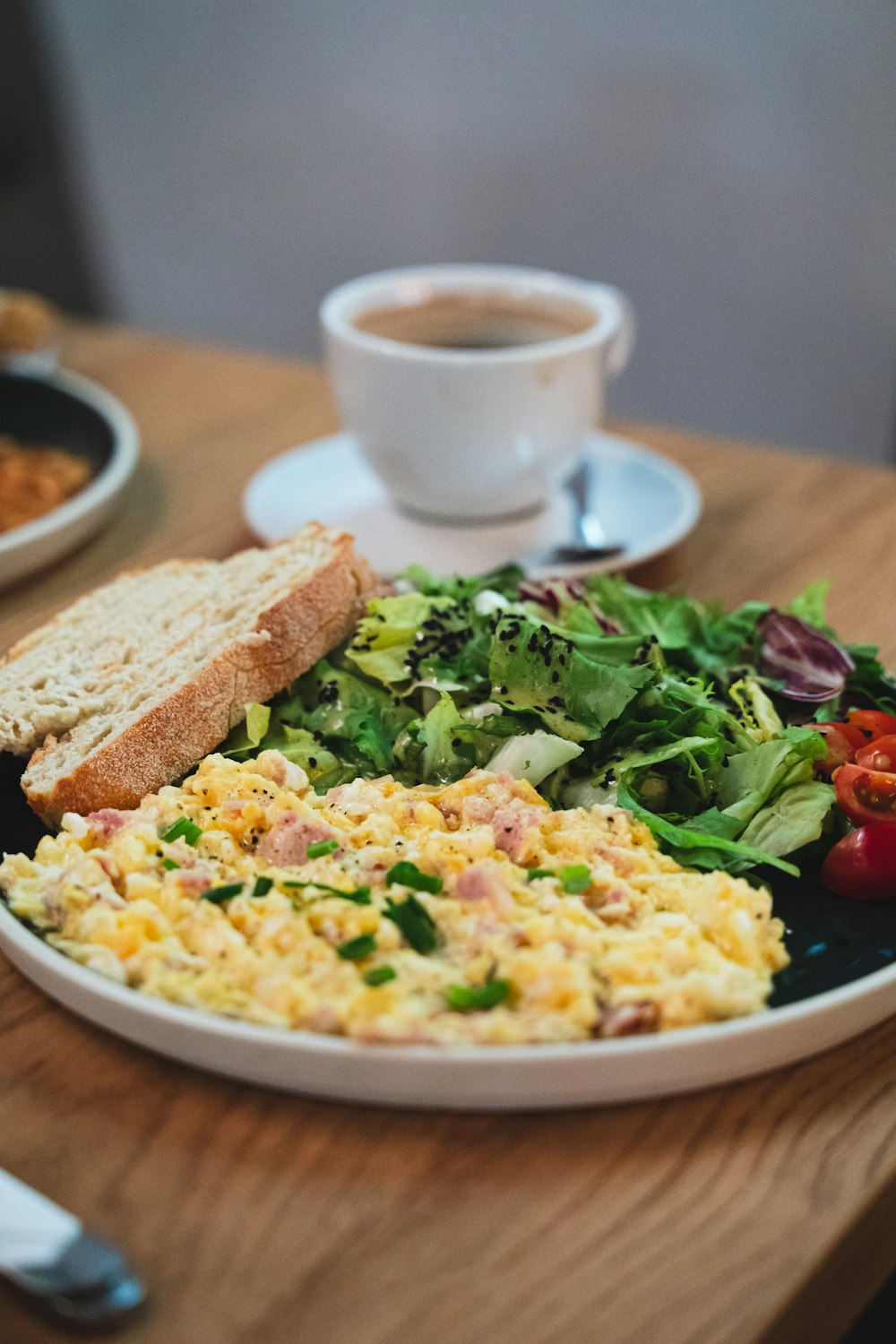 a plate of food on a table next to a cup of coffee