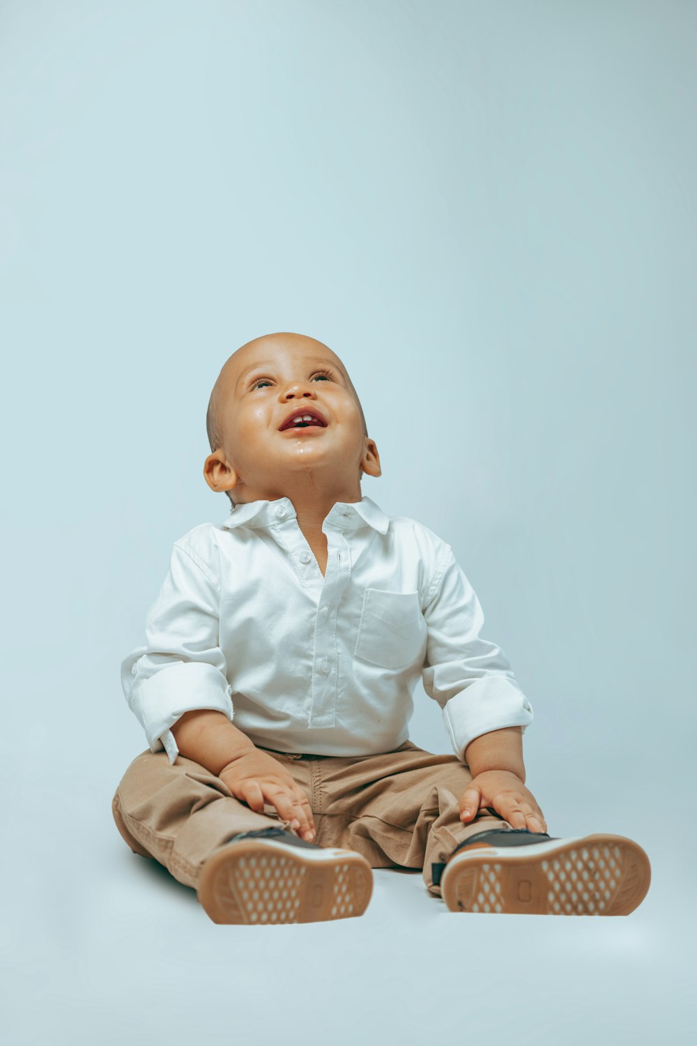 a baby sitting on the floor with a pair of shoes