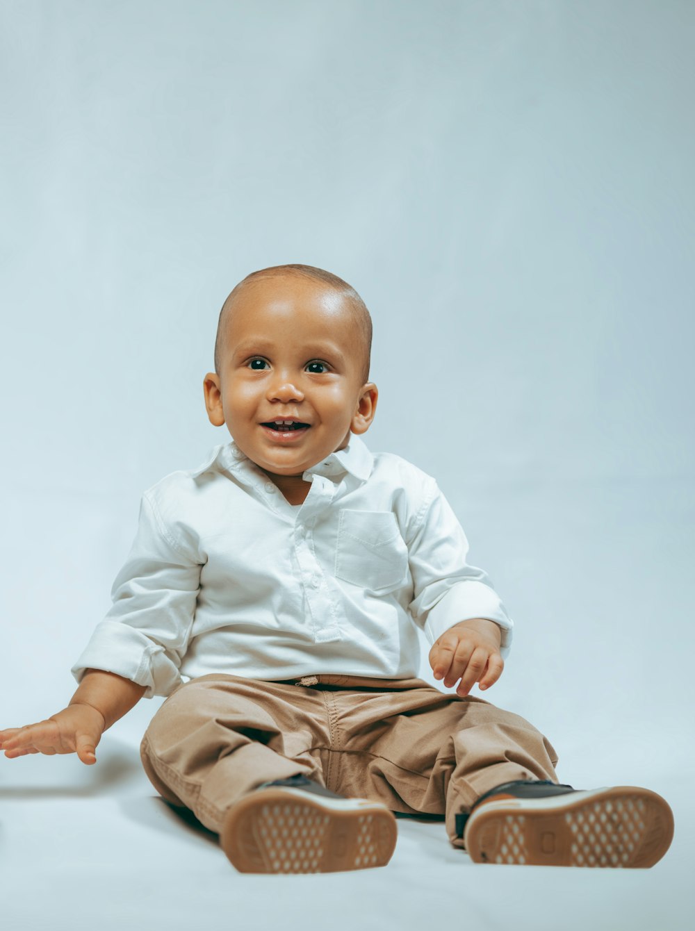 a baby sitting on the ground with his hands out