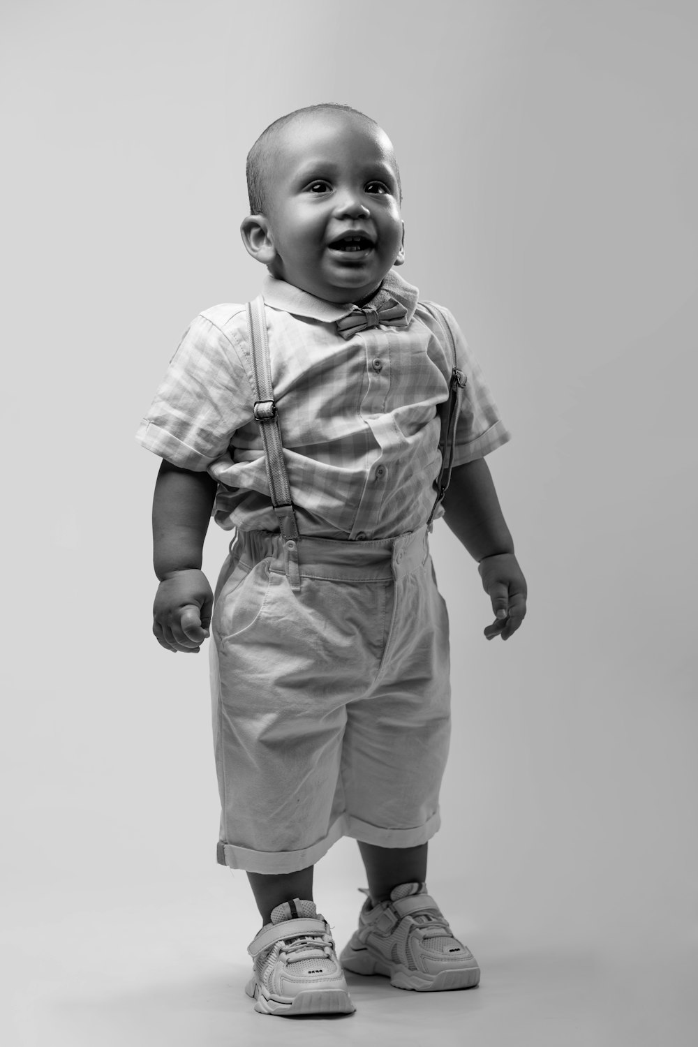 a black and white photo of a baby in overalls