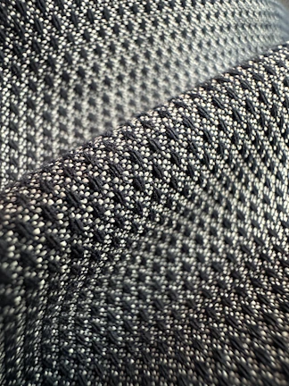 Close-up of intricate handwoven textile art showcasing layered textures in monochrome tones
