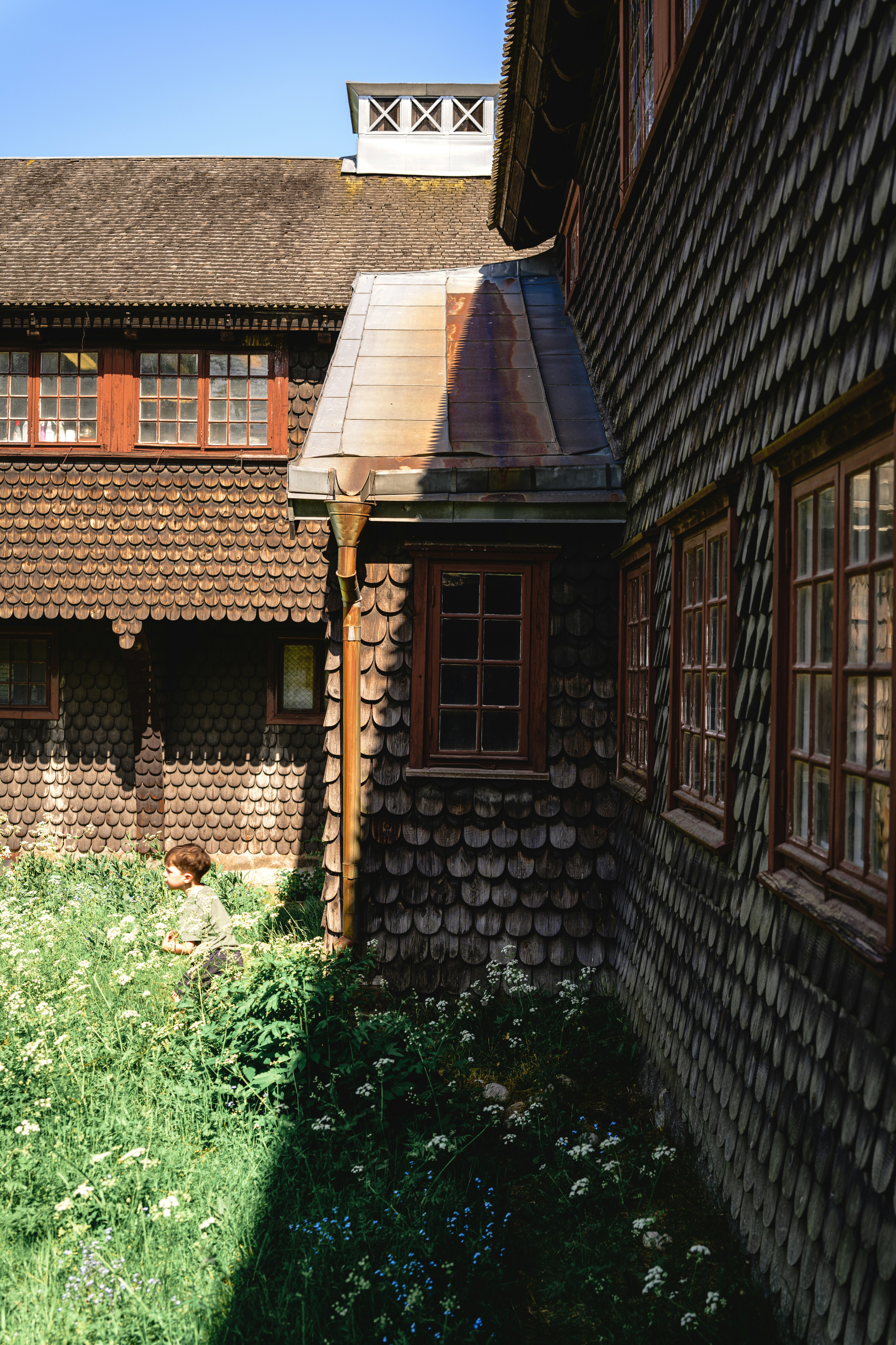 ein Gebäude mit einem braunen Dach neben einer grünen Wiese