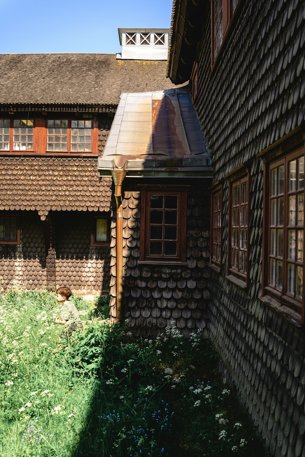 a building with a brown roof next to a green field