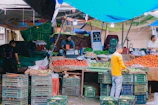 A bustling stall filled with colorful fresh fruits and vegetables under a bright tent.