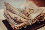 An open Bible with worn pages next to a pair of spurs and a feathered quill.
